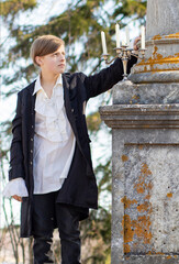 A young man in a white Victorian shirt against the background of a marble column in a candlestick
