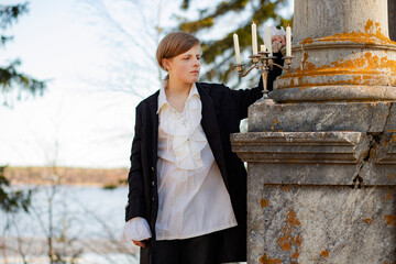 A young man in a white Victorian shirt against the background of a marble column in a candlestick