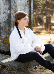 A young man in a white Victorian shirt seated at a marble monument