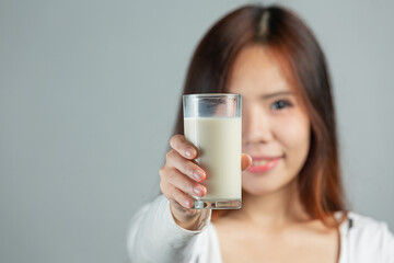 young woman  hands holding glass of milk on gray backgroud