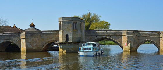Historic bridge over the river Ouse at St Ives Cambridgeshire with river cruiser 