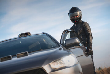 Rally car driver concept. A man in the helmet is standing near the car outdoors.