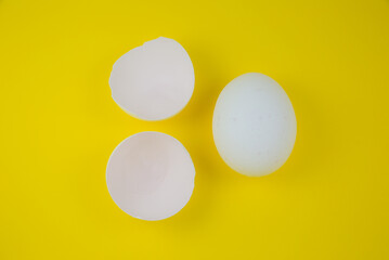 White egg and eggshell on the yellow background. Copy space. Minimalism, original and creative photo. Beautiful wallpaper. Easter holidays.