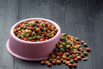 dry dog food in bowl on dark wooden backgroud