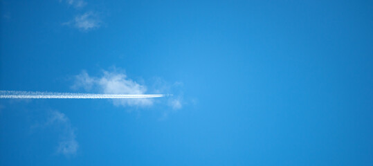 A plane flies through a white cloud in a blue sky