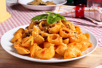 Pasta italiana. Delizioso piatto di pipe rigate condite con sugo di pomodoro, basilico ed asparagi selvatici.
