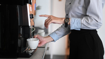 Close up view of young woman making coffee with coffee machine during office break time. - Powered by Adobe