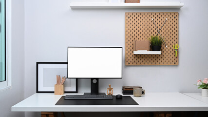 Home office workspace with computer, digital tablet and office supplies on white table.