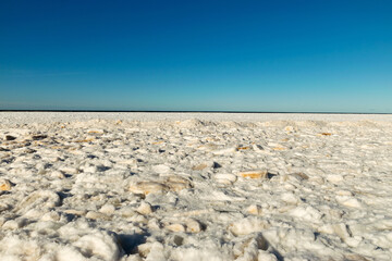 Fototapeta na wymiar winter landscape by the sea, ice pieces of different sizes, sea horizon in the distance, blue sky