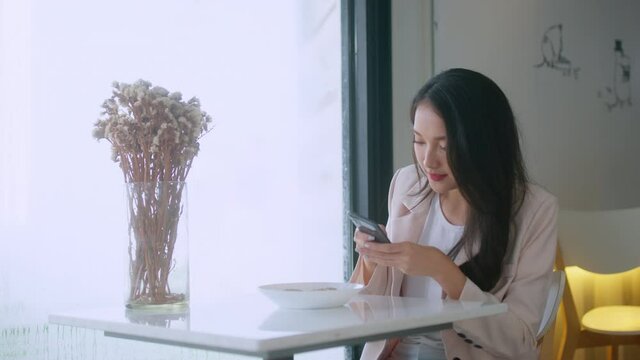 young attractive asian female wear casual cloth hand use smartphone and laptop device comminication social contact in cafe restaruant sit at counter next to big window daylight
