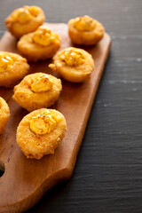 Homemade Deep-fried Deviled Eggs with Paprika on a Rustic Wooden Board, side view. Copy space.