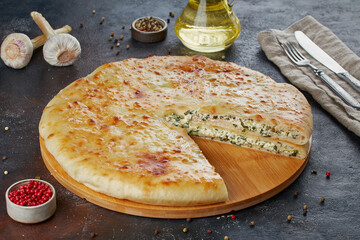 Traditional Caucasian dish - Ossetian pies with cheese, potatoes, herbs, cottage cheese, cherries, beef, mushrooms, dark background