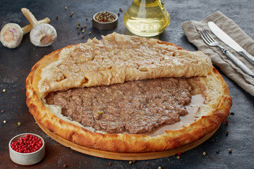 Traditional Caucasian dish - Ossetian pies with cheese, potatoes, herbs, cottage cheese, cherries, beef, mushrooms, dark background