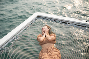 Woman lying on a pier with sea background, sit on the net by the sea.