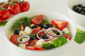 Greek salad with feta cheese, olives, juicy tomatoes, red pepper, red onion, cucumber and lettuce. Concept for healthy nutrition. Tasty and healthy vegetarian meal.