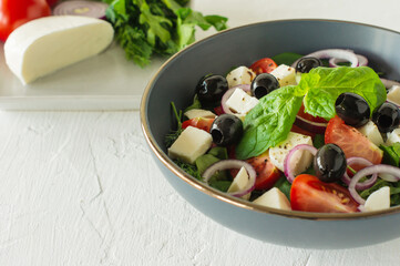 Greek salad. Fresh vegetable salad with cucumbers, tomatoes, olives, onion, bell pepper, feta cheese, lettuce and herbs, dressed with salt, pepper and olive oil. Horiatiki salad