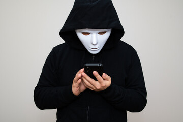 Hacker with anonymous mask holding his phone