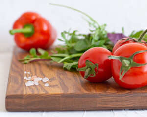 Fresh tomatoes, basil, micro-village, pepper on wooden table.