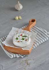 Baked camembert cheese on wooden board with baguette bread. Delicious cheese on a wooden plate. Food for wine. Hand dipping bread in cream cheese