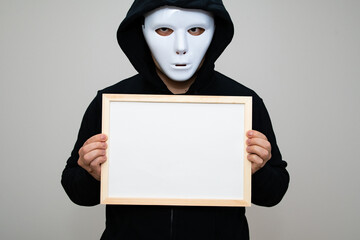 Hacker with anonymous mask holding a framed blank white board