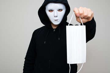 Hacker with anonymous mask holding a surgical mask