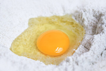 Raw egg yolk on whole wheat flour mixing grains, Preparation homemade ingredients dough used to make bakery, Pastry, Bread, Pasta, Noodles and Dumpling.