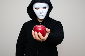 Hacker with anonymous mask holding an apple with his left hand