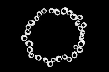 A circle of toy eyes on a black background
