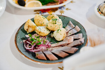 traditional Russian snacks. herring with onions and boiled potatoes. serving the table. Cooking for a festive dinner.