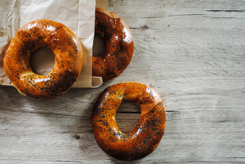 Sweet bagels with poppy seeds lie on a wooden table.