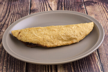 A quesadilla on a gray plate, ready to be prepared. Typical Mexican food