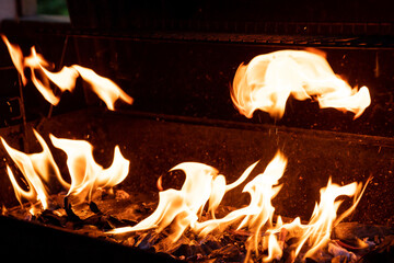 Fototapeta premium Hot BBQ Grill and Burning Fire. You can see more BBQ, grilled food, flames and fire.Empty Flaming Charcoal Grill With Flames Of Fire On Black Background Closeup. Summer Outdoor Barbeque Party