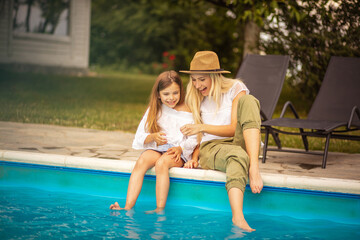 Fototapeta na wymiar Mother and daughter having fun by the pool.