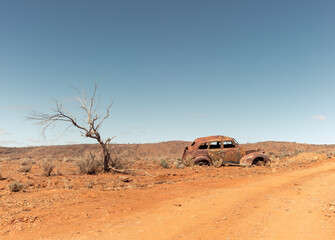 The rusted abandoned wreck of an old car in a remote area of Australian Outback on a rural dirt road near Fowlers Gap, NSW