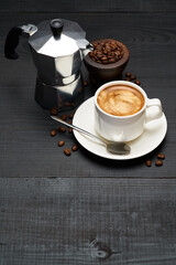Cup of espresso coffee and mocha coffee maker on dark wooden background