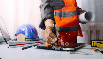 Two colleagues discussing data working and tablet, laptop with on on architectural project at construction site at desk in office