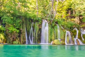 Fototapeta na wymiar Waterfalls flowing into the crystal water of Lake Plitvice