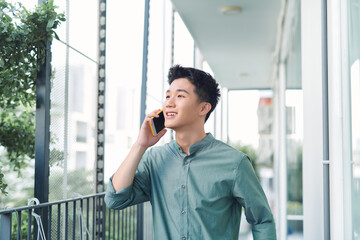 A portrait of man standing at a balcony making a phone call.