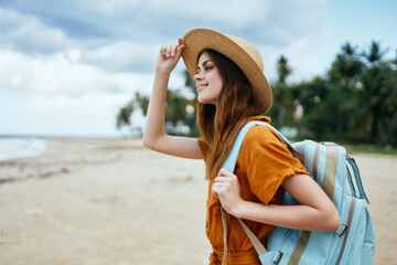 woman travels on the beach near the sea with a backpack on her back