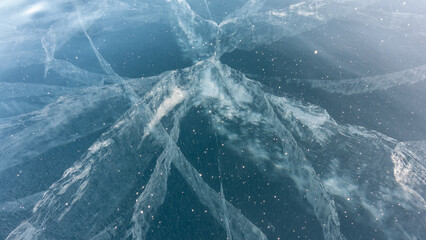 Transparent blue ice of Lake Baikal. On the smooth surface, many cracks are visible, going deep....