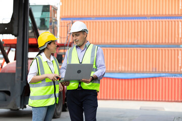 factory workers or engineers using laptop computer and talking about project work in containers warehouse storage