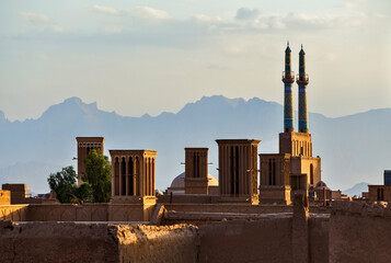 View over the roofs of the old city of Yazd in Iran with mosques and wind catchers (wind tower) in the distance.