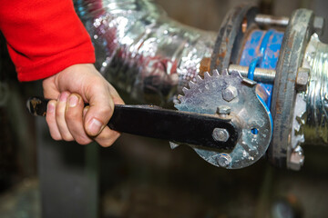 Overlapping a valve in an industrial water supply pipe. Prevention and elimination of problems in the pipeline. Close-up. Unrecognizable person
