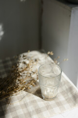 a glass coffee cup on a checkered cotton napkin. sunny day. dry flowers