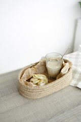 Handmade home decor. oval jute basket with wooden bottom, tray, food stand, table setting. the concept of home decor and comfort in the eco style. a rice cake with a banana and a clear glass of latte.