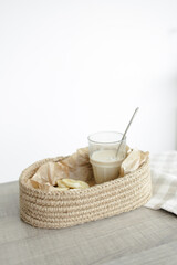 Handmade home decor. oval jute basket with wooden bottom, tray, food stand, table setting. the concept of home decor and comfort in the eco style. a rice cake with a banana and a clear glass of latte.