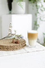 Handmade home decor. round jute napkins, hot plate, table setting. the concept of long-term decor and comfort in the eco style. chocolate candy truffle. A clear glass of latte coffee. Checkered linen 