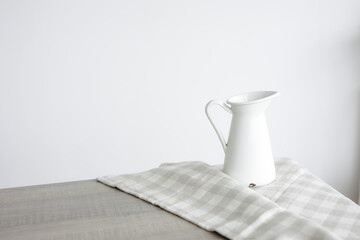 milk jug with white handle on a checkered napkin on a white background.