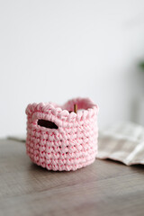 rectangular basket made of pink knitwear, on the table. white background