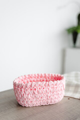 Fototapeta na wymiar rectangular basket made of pink knitwear, on the table. white background